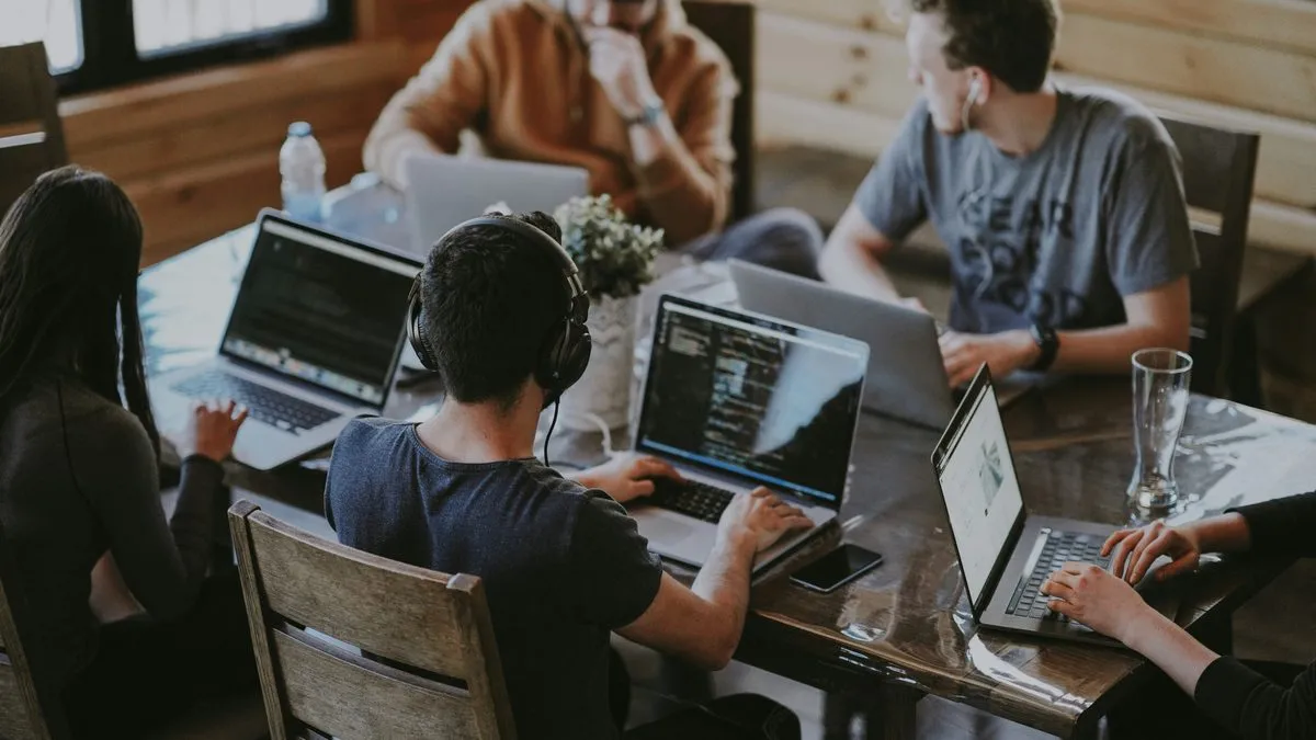 Team collaborating on laptops together in a warm coworking space